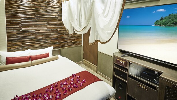 Een hotelkamer met een bed, een televisie en uitzicht op een strand.