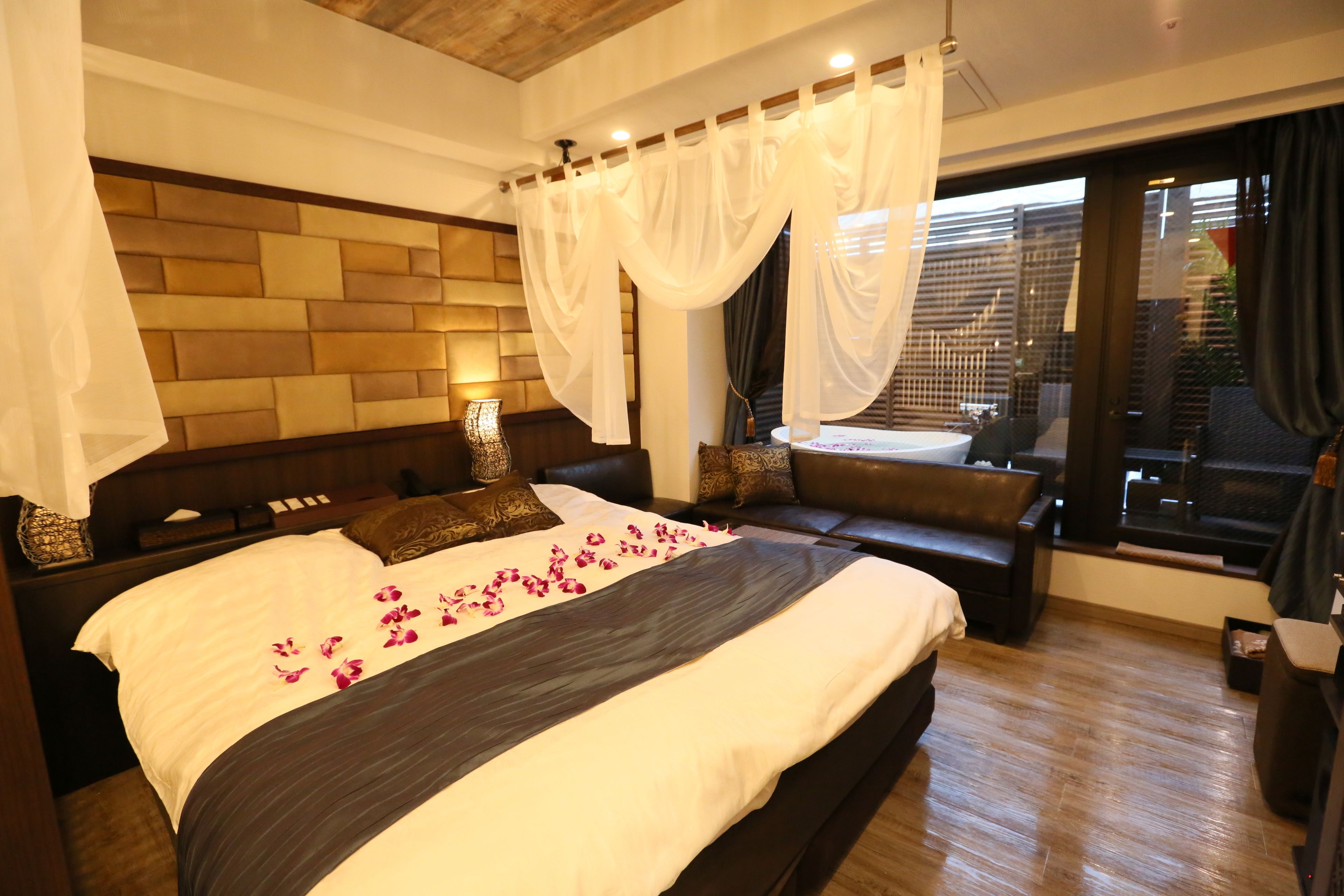 Un dormitorio con una cama grande, un banco, vista al exterior y una pared de ladrillo.