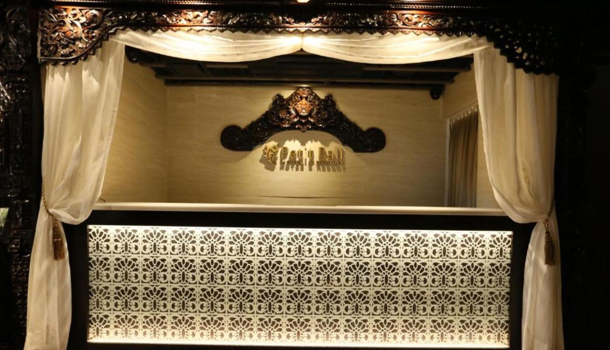 Quarto com cama de dossel, cabeceira de madeira ornamentada e persiana com padrão.