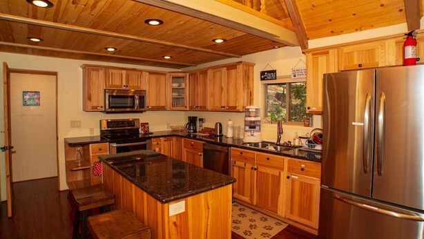 A modern kitchen with wooden cabinets, a stainless steel refrigerator, and a central island. - *Peaceful getaway *Close to Goldwater Lake *Cabin (Prescott)