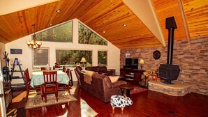 A cozy living room with a fireplace, wooden flooring, and a dining area with a table and chairs. - *Peaceful getaway *Close to Goldwater Lake *Cabin (Prescott)