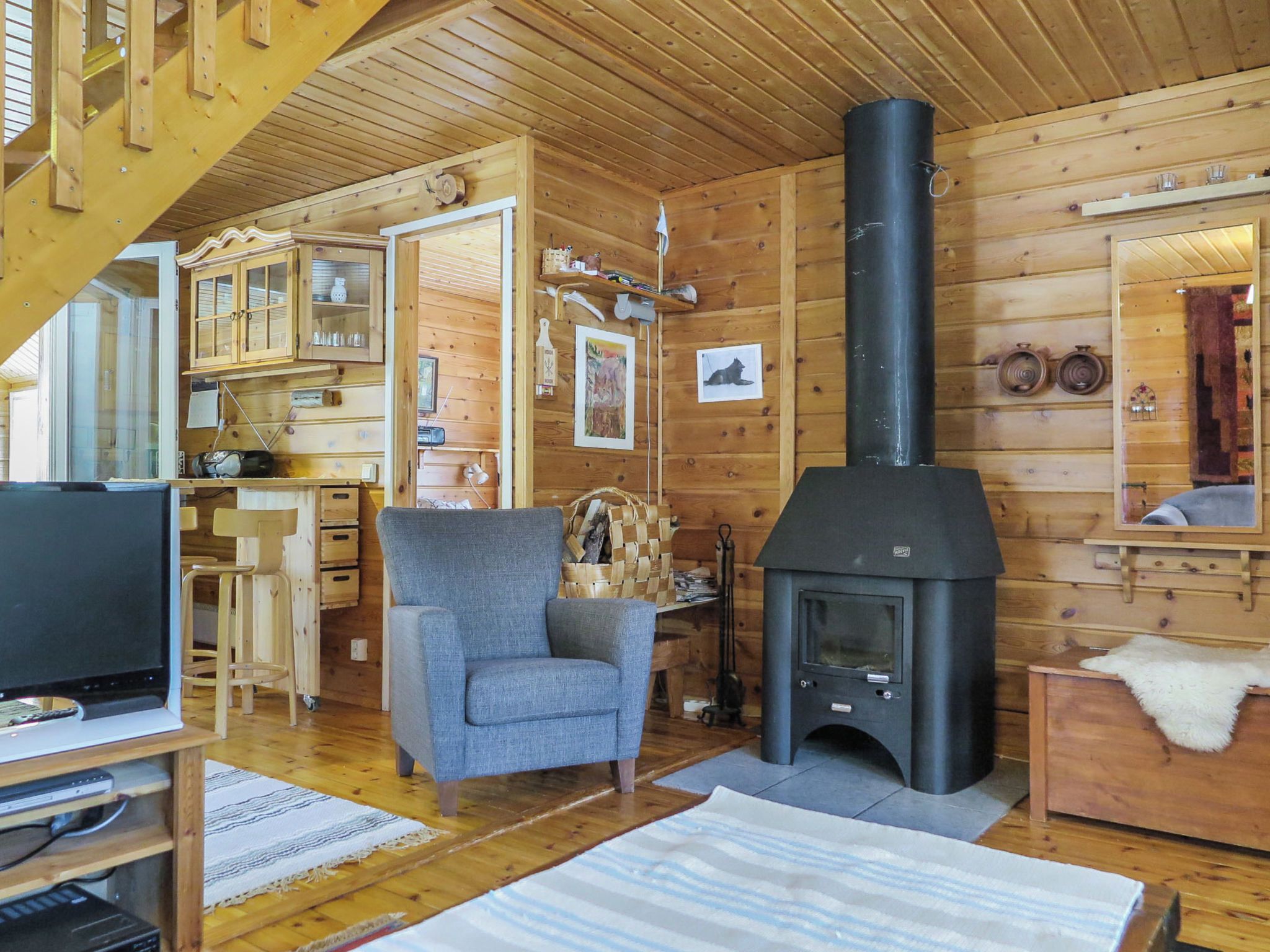A cozy cabin interior with a fireplace, wooden walls, a television, and a comfortable seating area.