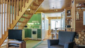 A cozy cabin interior with a wooden staircase, a dining area, and a kitchen with green cabinets.
