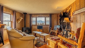 Een gezellig chaletinterieur met een leren bank, een houten tafel, een televisie en een open haard.
