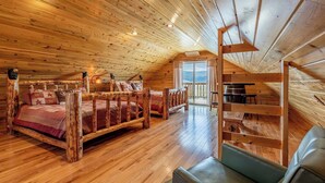 Een interieur van een blokhut met een houten bed, een bank en een eethoek.