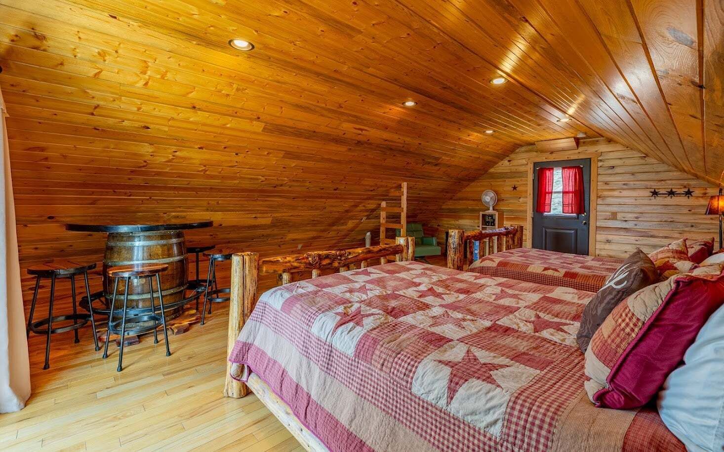 Un dormitorio de cabaña de madera con una cama grande, techo de madera y un rincón bar.