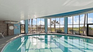Piscina interior con vistas despejadas al exterior, incluyendo palmeras y cielo despejado.