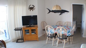 A dining area with a table, chairs, a television on a cabinet, and decorative wall art.