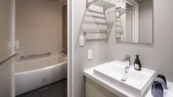 A modern bathroom with a white bathtub, a sink with a mirror above it, and a towel rack.