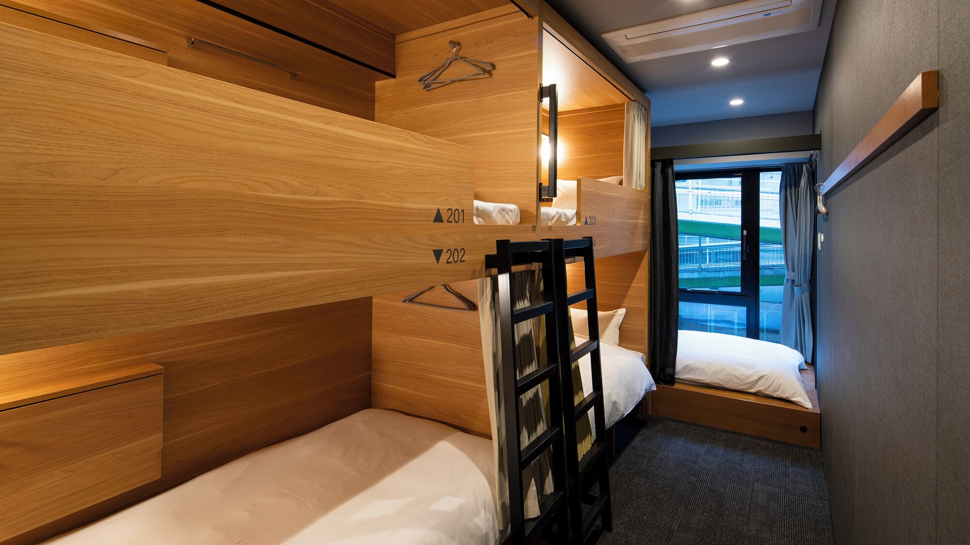Une chambre d’hôtel compacte avec des lits superposés, un petit bureau et une fenêtre donnant sur un paysage agréable.
