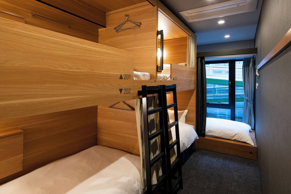 Habitación de hotel compacta con literas, un escritorio pequeño y una ventana con vistas.
