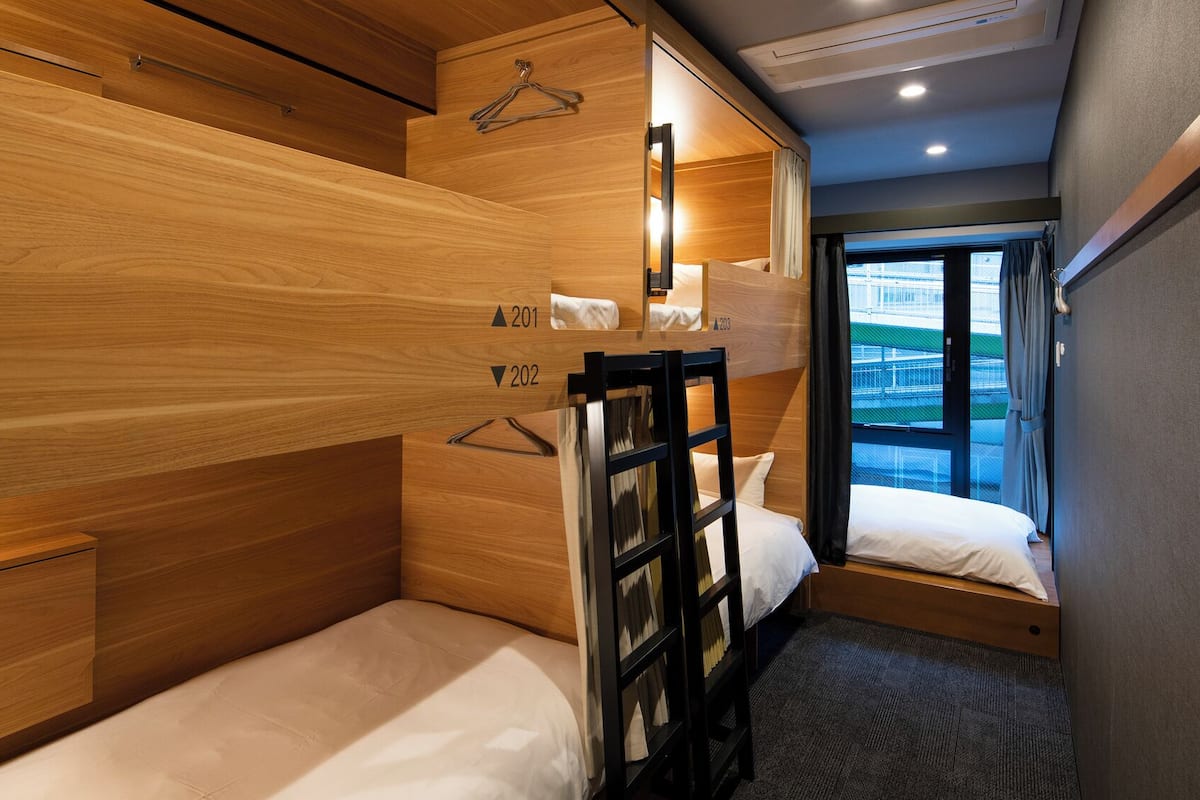 Une chambre d’hôtel compacte avec des lits superposés, un petit bureau et une fenêtre donnant sur un paysage agréable.