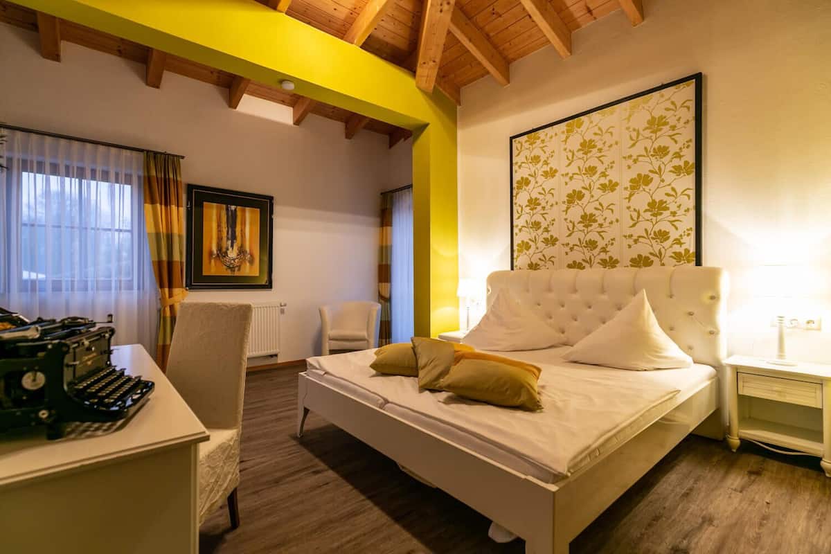 Ein Schlafzimmer mit einem Bett, einem Schreibtisch mit Schreibmaschine, einem Sessel und einer Heizung.