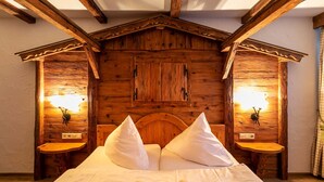 A wooden cabin-style bedroom with a large bed, two bedside tables, and wall-mounted lights. - Forsthof (Steinheim an der Murr)