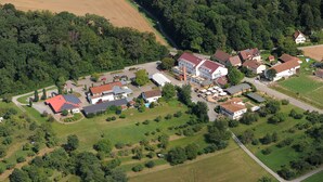 An aerial view of a small village with a mix of residential and commercial buildings, surrounded by green fields and forests. - Forsthof (Steinheim an der Murr)
