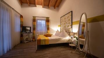 A bedroom with a bed, a desk with a computer, a TV, and a mirror.