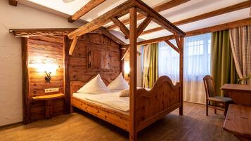 A wooden four-poster bed with a headboard, a wooden nightstand, and a wall-mounted light fixture.