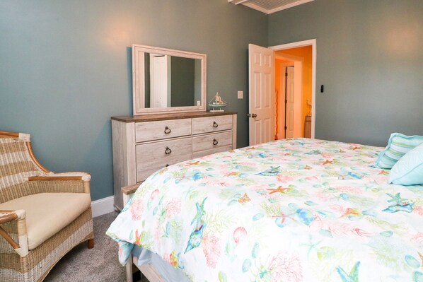 A bedroom with a bed, a dresser, a chair, and a door.