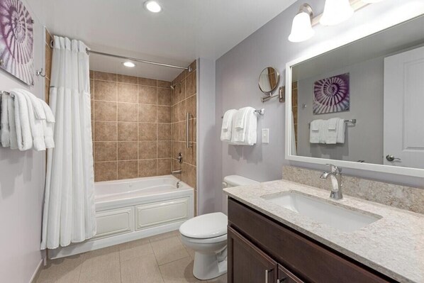 A bathroom with a bathtub, toilet, sink, and a large mirror. - Cherry Grove Beach Resort best in SC. (North Myrtle Beach)