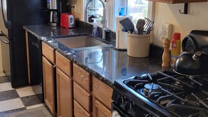 A kitchen with wooden cabinets, a black refrigerator, a stove, and a window with a view.