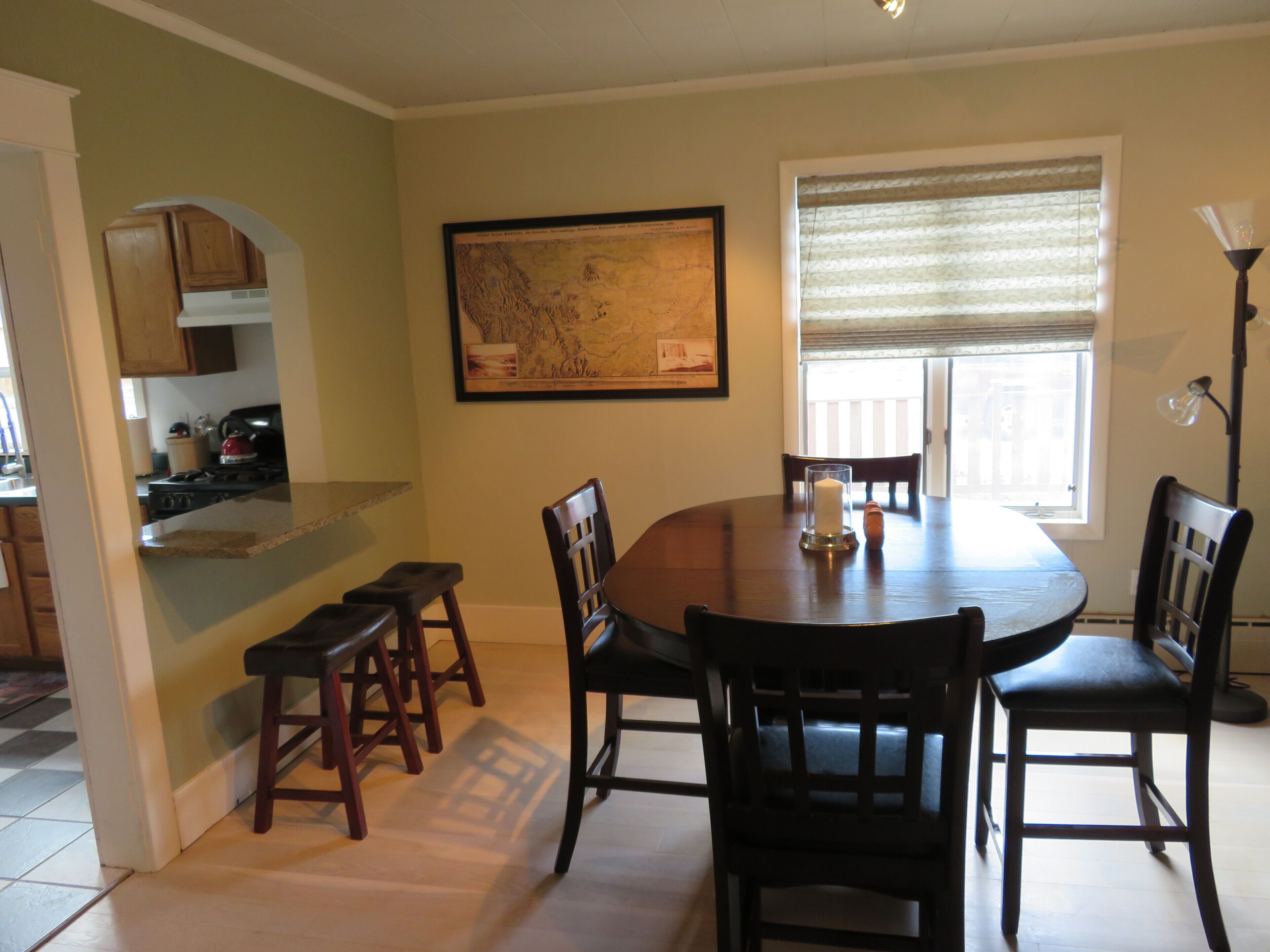 A dining area with a round table, six chairs, a candle, and a map on the wall.