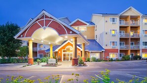 A hotel with a covered entrance, multiple balconies, and a parking lot.