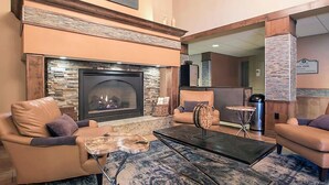 A lobby with a stone fireplace, leather sofas, a coffee table, and a small side table.