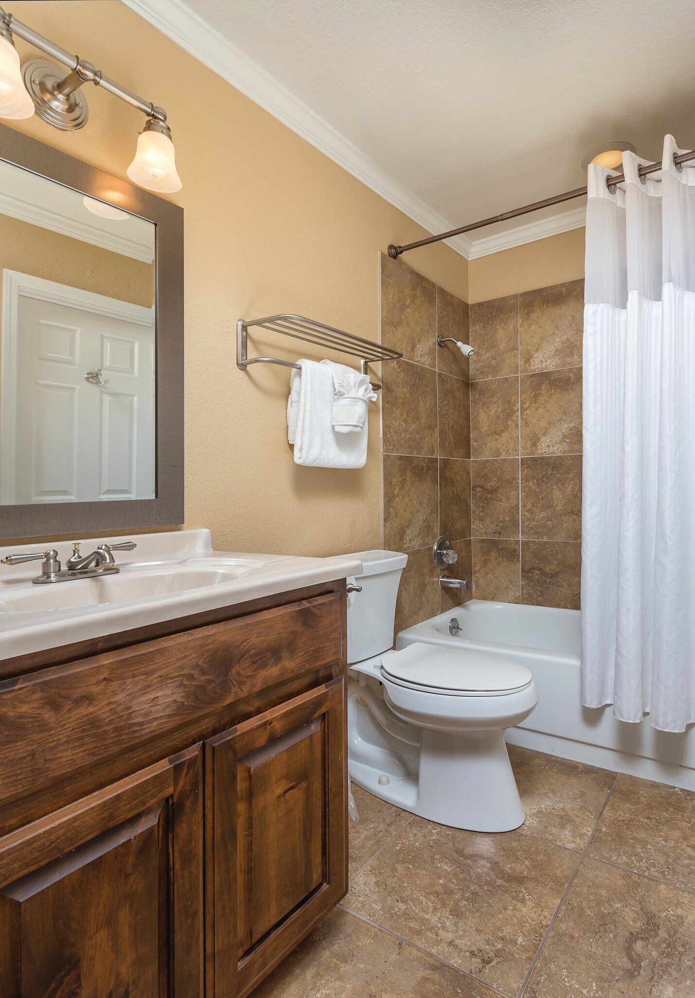 A bathroom with a wooden vanity, a white sink, a toilet, and a bathtub with a shower curtain.