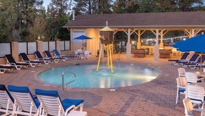 Un espace piscine comprenant des chaises longues, un jacuzzi et un coin salon abrité.