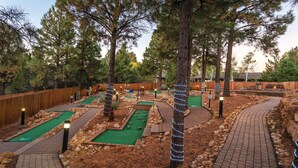 Un parcours de minigolf comportant plusieurs pistes, des clôtures en bois et des arbres.