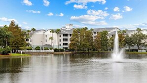 Un hotel con vista al lago, una fuente y una hilera de edificios de estilo arquitectónico uniforme.