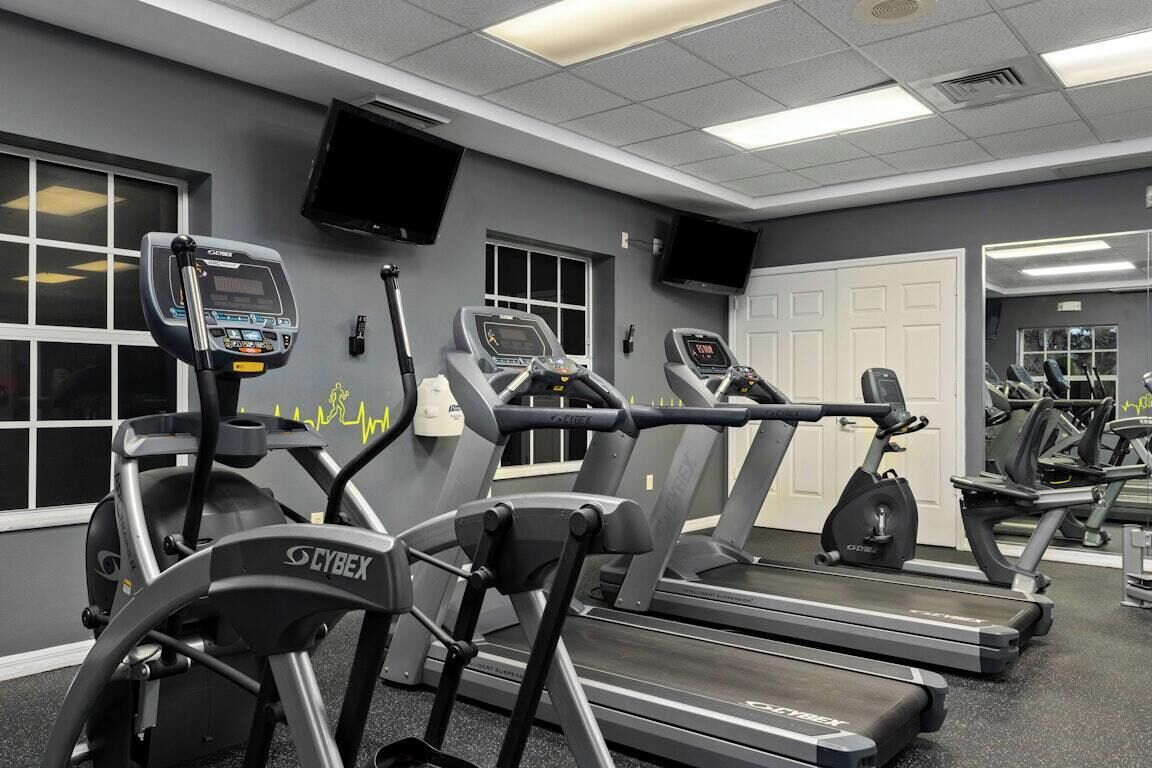 A gym with treadmills, stationary bikes, and a mirrored wall.