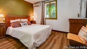 Una camera da letto con un letto di legno, un comodino con una lampada, una cassettiera e una finestra con tende.