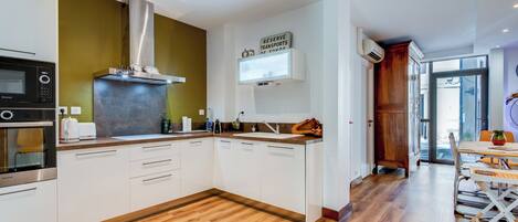 Una cocina moderna con armarios blancos, una campana extractora de acero inoxidable y suelo de madera.