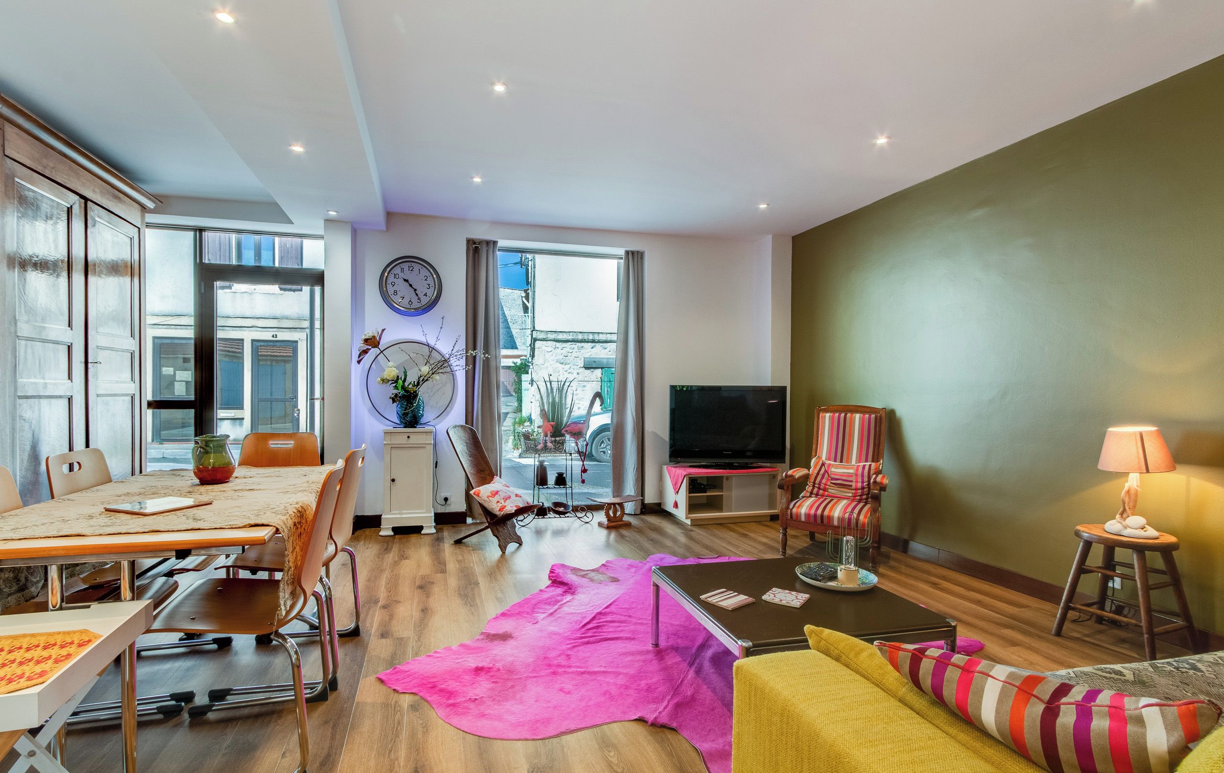 Ein modernes Wohnzimmer mit Essbereich, großem Fenster, Fernseher und einer Couch.