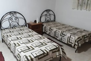 Two single beds with metal frames and patterned bedspreads are positioned side by side.