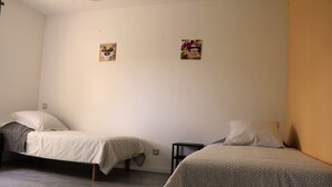 Een kamer met twee eenpersoonsbedden, een klein tafeltje en twee aan de muur bevestigde foto's.