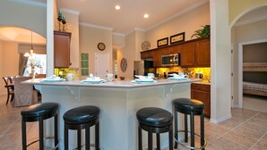 Une cuisine moderne dotée d’un îlot central, de tabourets de bar et d’un coin repas avec des chaises.