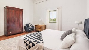A bedroom with a large bed, a wardrobe, a desk, and a window with curtains. - Binicalaf · ❤️Finca Binicalaf Vell (Maó)