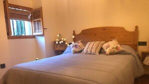 Ein Schlafzimmer mit einem großen Bett, einem Holz-Kopfteil und einem Nachttisch mit Lampe.