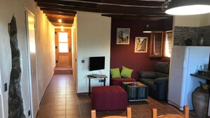 Ein kompakter Wohnraum mit Küche, Essbereich mit rotem Tisch und Stühlen sowie einer Sitzecke mit Sofa und Kissen.