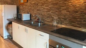 Eine Küche mit Steinrückwand, einem Einbauofen, einem Spülbecken und einer Mikrowelle.