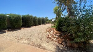 A gravel driveway leading to a house with a concrete sidewalk on the left. - 15 Grenadier Street - family home with all that you need (EXMOUTH)