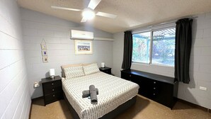 A bedroom with a bed, a ceiling fan, an air conditioner, a window with curtains, and a framed picture on the wall. - 15 Grenadier Street - family home with all that you need (EXMOUTH)