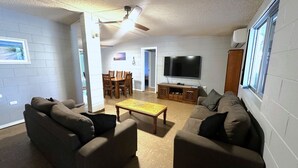 A living room with two sofas, a coffee table, a TV, and a dining area with chairs and a table. - 15 Grenadier Street - family home with all that you need (EXMOUTH)