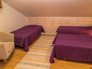 A room with two beds, a chair, and a wooden ceiling. - Karitahko a 2 by Interhome (Nilsiä)