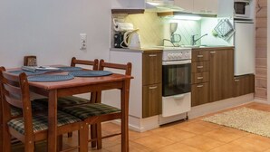 Une cuisine compacte comprenant une table à manger, des chaises, une cuisinière, un four, un four à micro-ondes et un petit plan de travail.