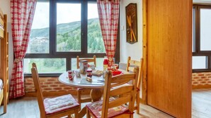 A cozy dining area with a round table, wooden chairs, and a view of a mountainous landscape through large windows. - Belleville Caron 3 - 624 by Interhome (Les Menuires)