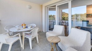 Een balkon met een eettafel, stoelen en een klein rond tafeltje.