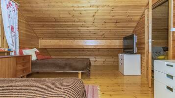 Una cabaña de madera con una cama en el altillo, un televisor y un aparador.